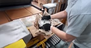Worker using paper void fill to protect a product during packing