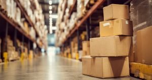 Stack of cardboard boxes of different sizes in a warehouse aisle, representing common shipping box formats used in Canada.