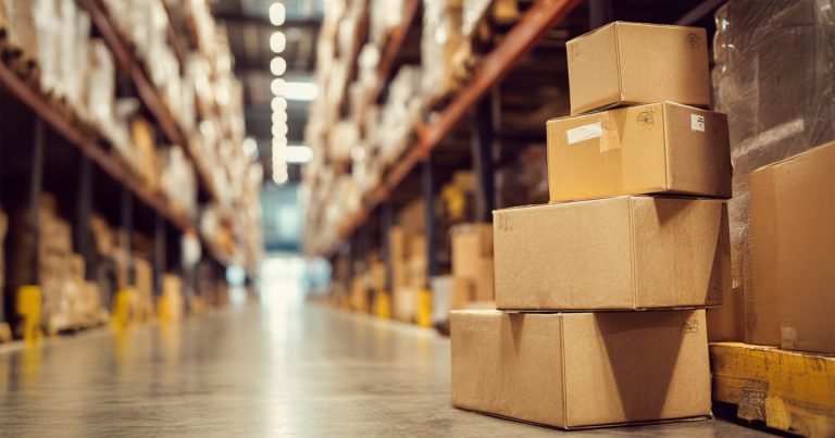 Stack of cardboard boxes of different sizes in a warehouse aisle, representing common shipping box formats used in Canada.